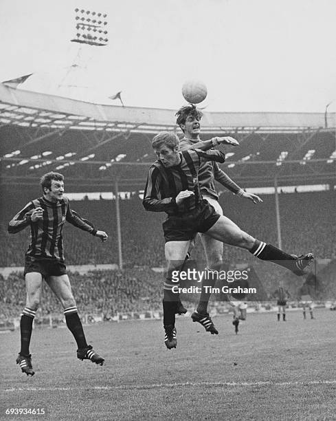 Alan Oakes of Manchester City challenges Allan Clarke of Leicester City for the ball in the air as Neil Young of Manchester City looks on during...
