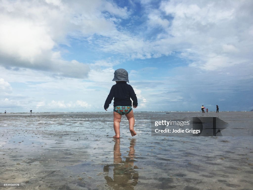 Young child walking alone on sand at the beach