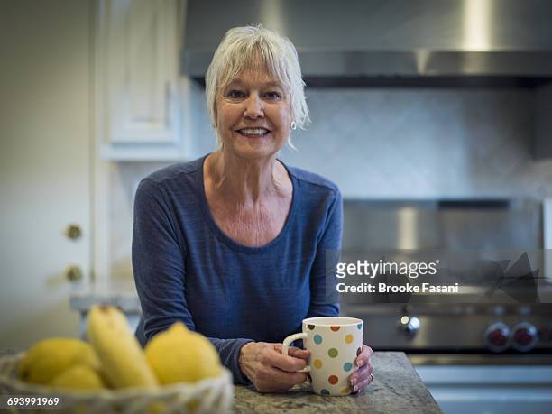 older woman in kitchen with coffee - grey hair cool woman stock-fotos und bilder