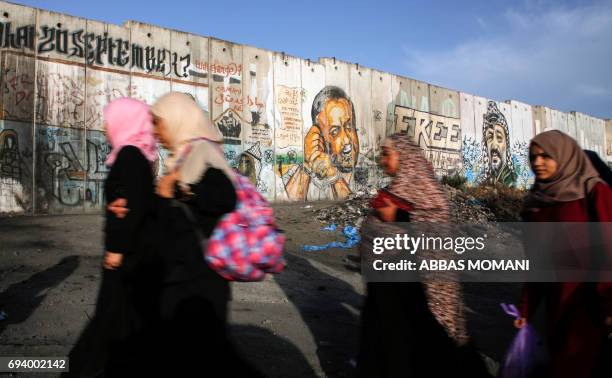 Palestinian women queue up past a mural of Fatah leader Marwan Barghuti, painted on a section of Israel's controversial separation wall next to...