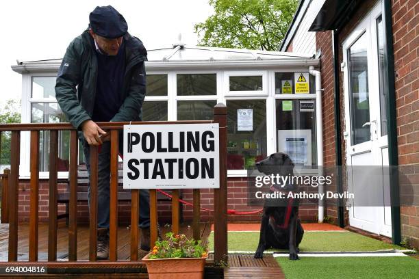 Voter ties the lead of Guia, a Labrador rescued from Ecuador, to a fence post outside a polling station in Stalybridge on June 8, 2017 in Greater...