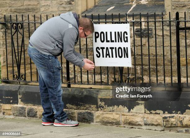 Polling station offical attaches a sign to railings as the polls open on June 8, 2017 in Saltburn-by-the-Sea, United Kingdom. Polling stations open...