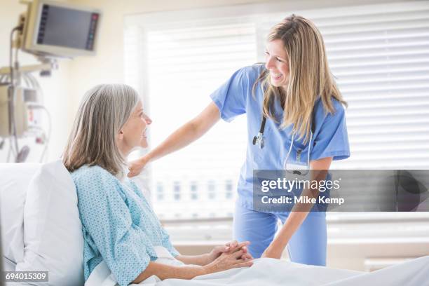 caucasian nurse talking with woman in hospital bed - doctor stethoscope patient whole body stock pictures, royalty-free photos & images