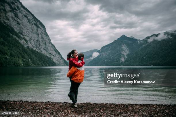 caucasian man hugging near mountain lake - couple laughing hugging stock pictures, royalty-free photos & images