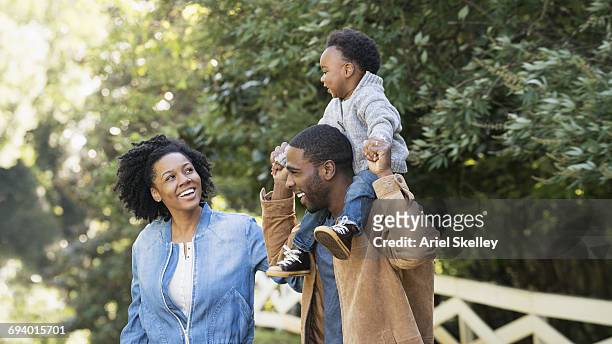 smiling black family in park - african american couple walking park ストックフォトと画像