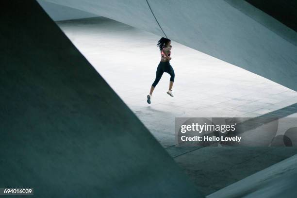 mixed race woman running under urban structure - mixed race woman stock-fotos und bilder