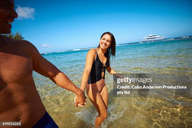 couple holding hands wading in ocean - mid section stock pictures, royalty-free photos & images