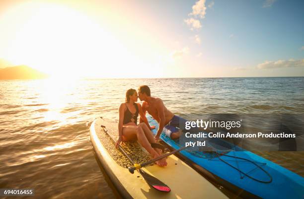 couple sitting on paddleboards rubbing noses in ocean - kiss booth stock-fotos und bilder