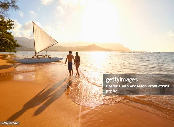 couple walking on beach near sailboat - hawaii fun fotografías e imágenes de stock