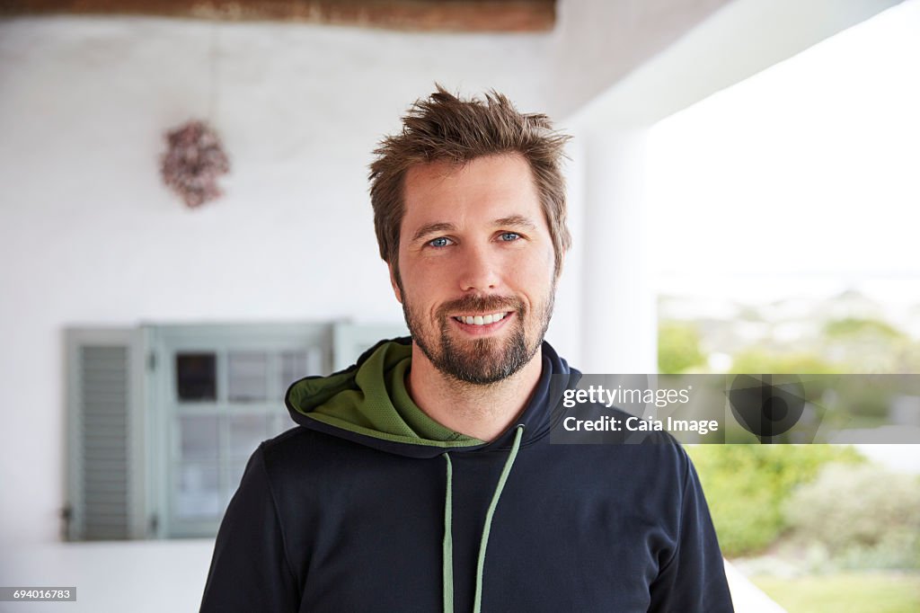 Portrait smiling brunette man wearing hoody on patio