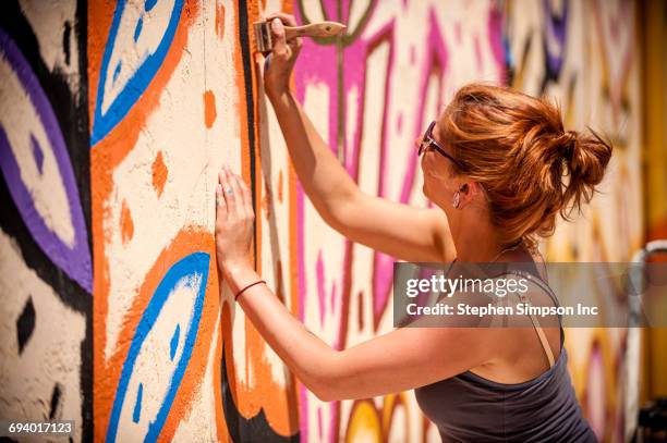 caucasian woman painting mural on wall - 芸術家 ストックフォトと画像