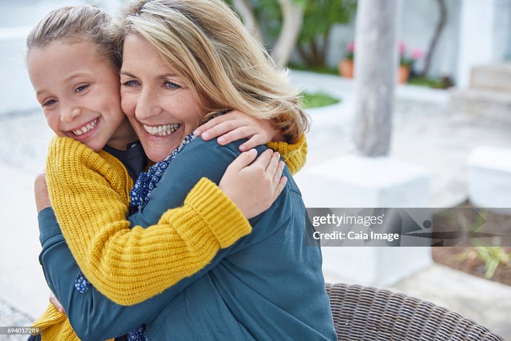 Enthusiastic grandmother and granddaughter hugging on patio