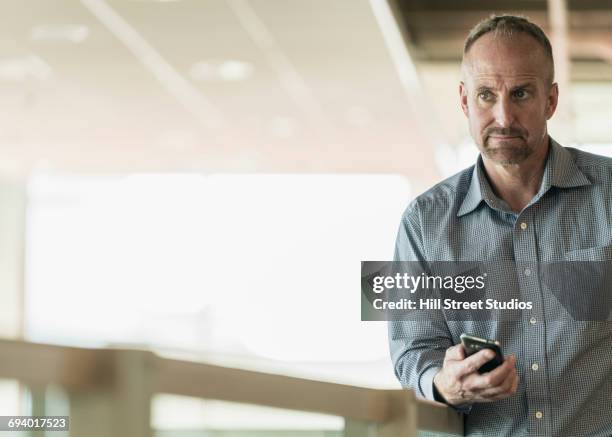 curious caucasian businessman holding cell phone - american red cross fotografías e imágenes de stock