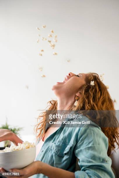 caucasian woman throwing popcorn into mouth - throwing stock pictures, royalty-free photos & images
