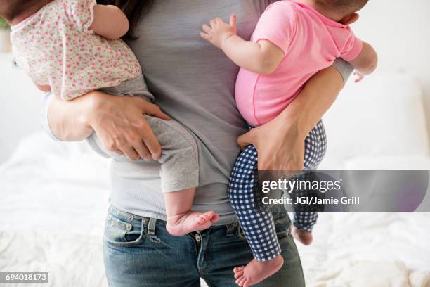 caucasian mother carrying twin baby daughters - handful stock pictures, royalty-free photos & images