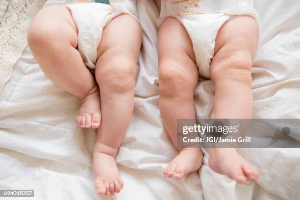 legs of caucasian twin baby girls laying on bed - gémellité photos et images de collection