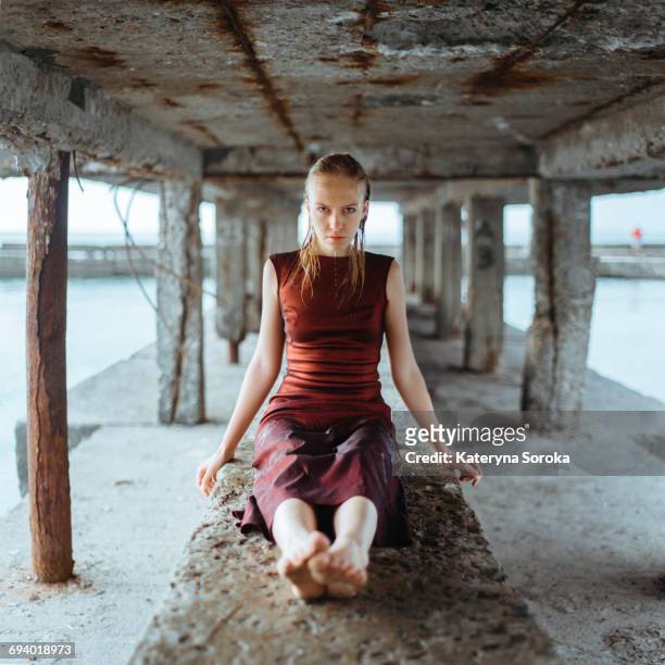 caucasian girl wearing wet dress sitting underneath dock - girls in wet dresses stock-fotos und bilder