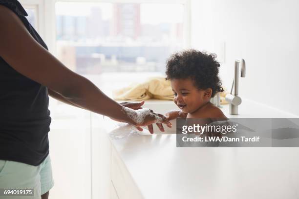 black mother bathing baby son in sink - baby bathtub 個照片及圖片檔