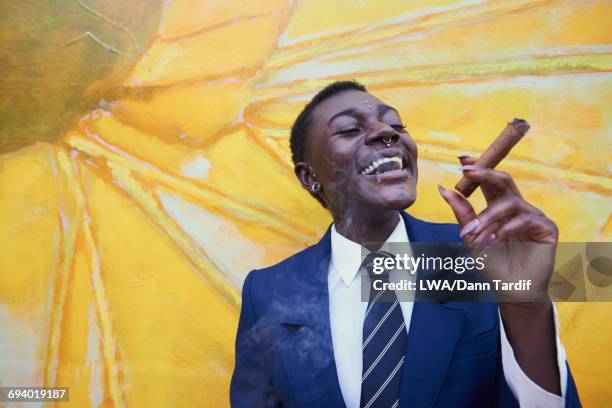 androgynous black woman smoking cigar near mural - pierced nose stock pictures, royalty-free photos & images