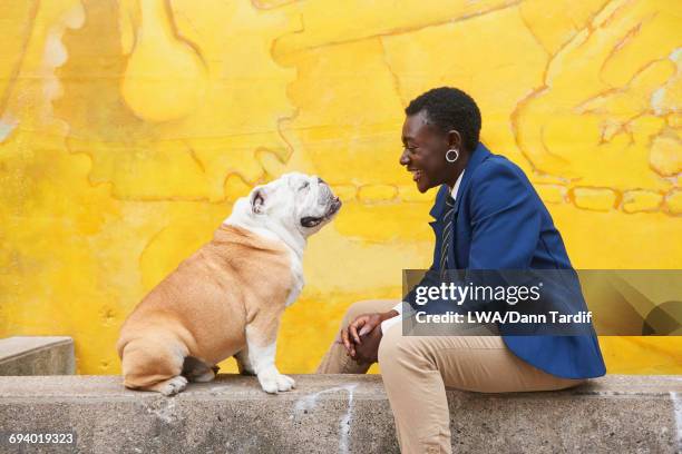 androgynous black woman sitting with dog near mural - daily life in toronto stock pictures, royalty-free photos & images