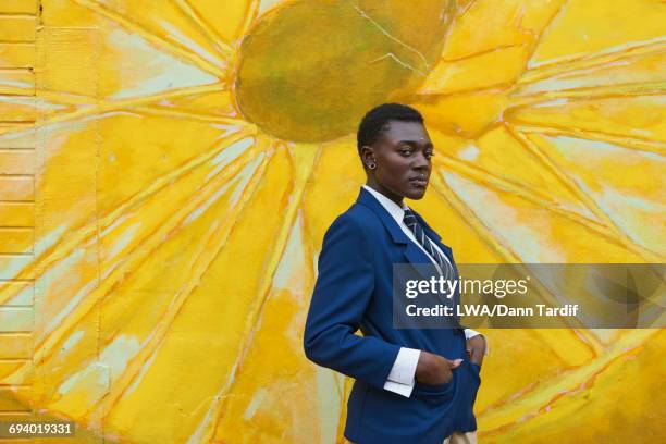 serious androgynous black woman standing near mural - black transgender stock-fotos und bilder