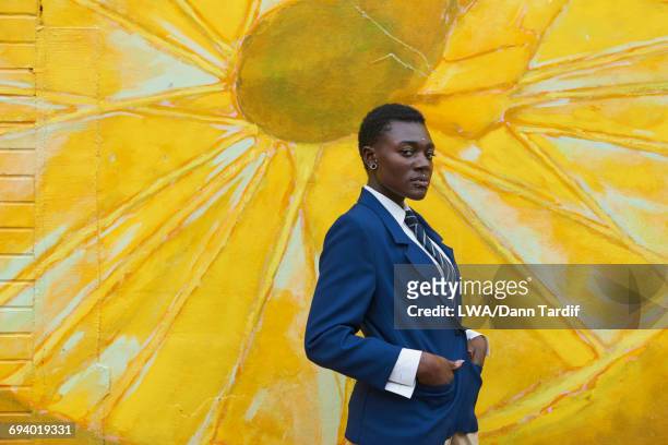 serious androgynous black woman standing near mural - transgender stock pictures, royalty-free photos & images