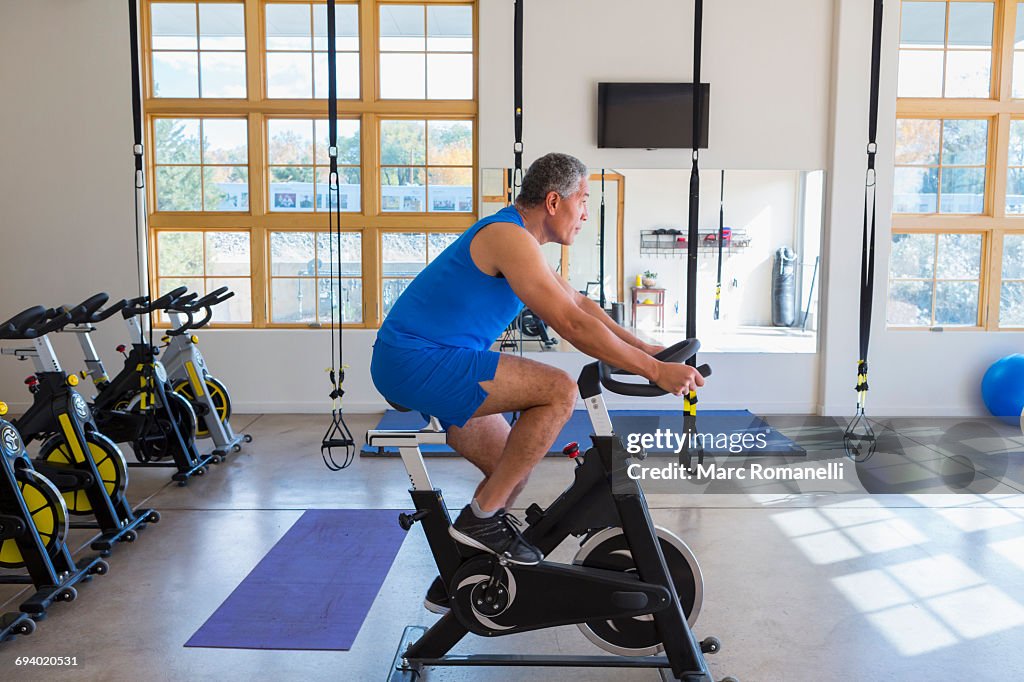 Mixed Race man riding stationary bicycle in gymnasium