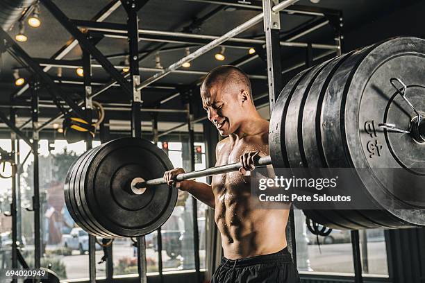 man lifting heavy barbell in gymnasium - barbell stock pictures, royalty-free photos & images