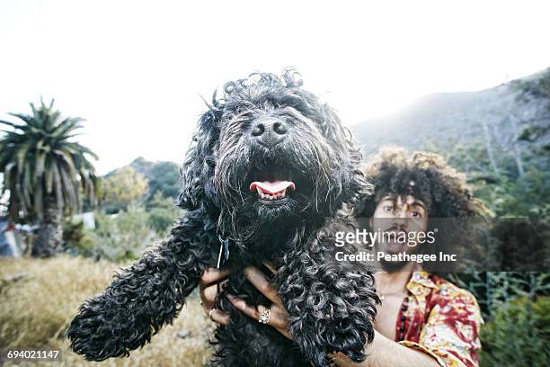 mixed race man holding shaggy dog - hairy man stockfoto's en -beelden