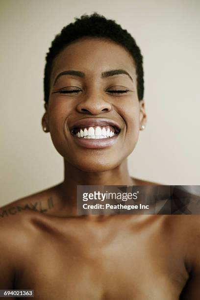 portrait of smiling black woman with eyes closed - tattoo shoulder stock-fotos und bilder