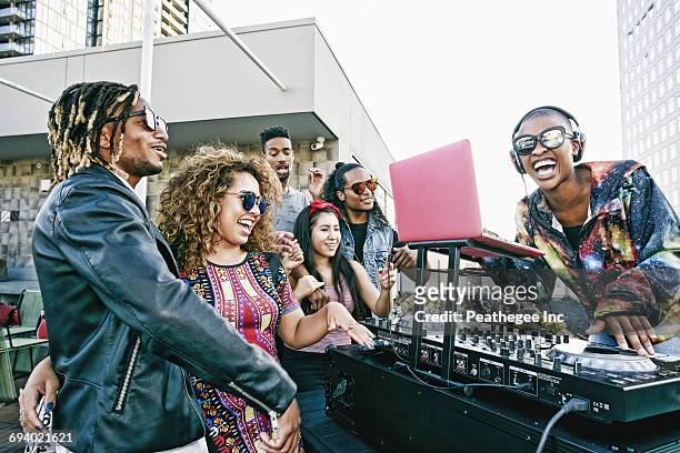 friends smiling with dj on urban rooftop - dj party stock-fotos und bilder