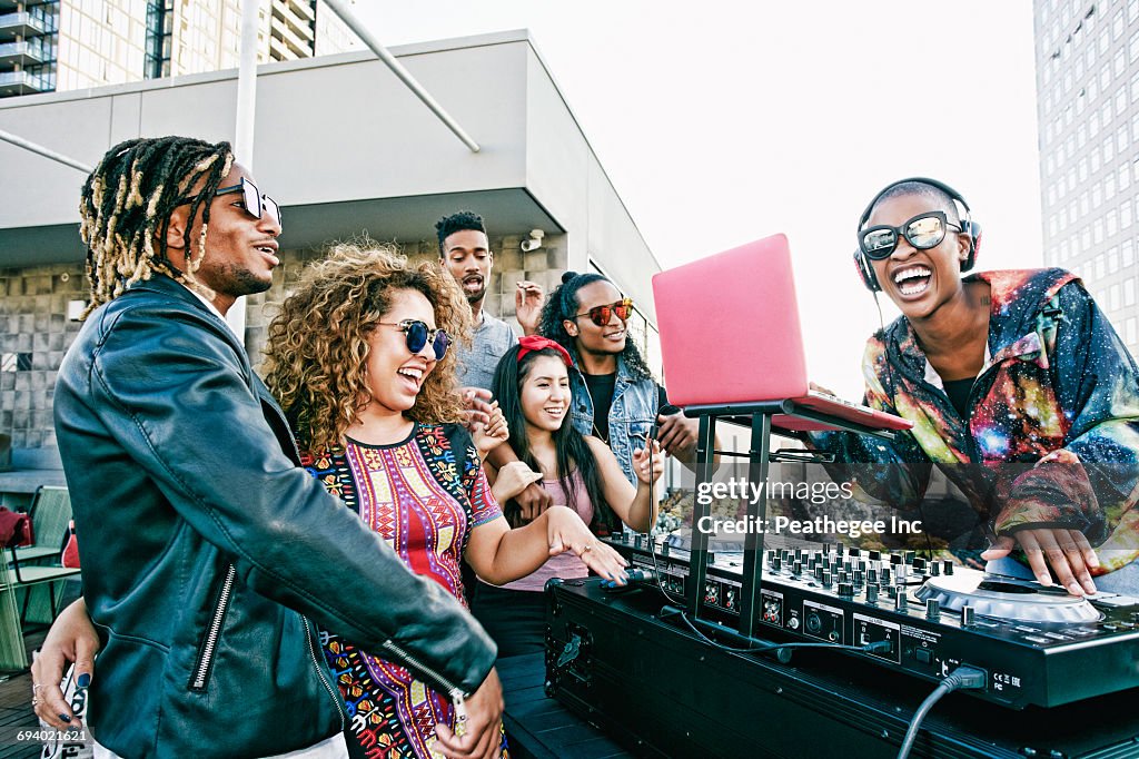 Friends smiling with DJ on urban rooftop