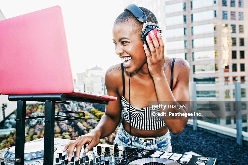 Black DJ laughing on urban rooftop