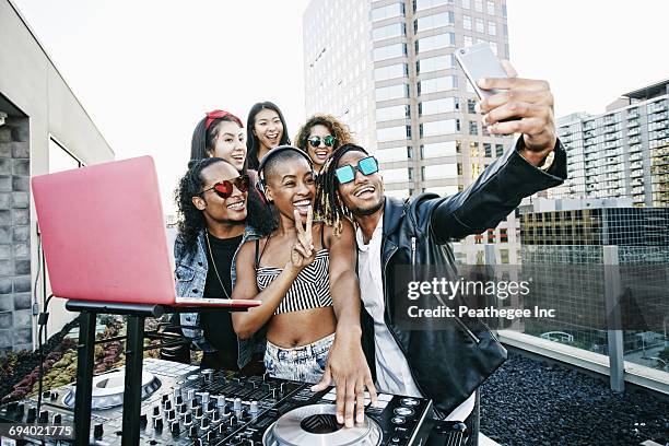 friends posing for cell phone selfie with dj on urban rooftop - dj portrait ストックフォトと画像