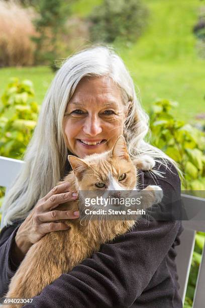 portrait of smiling caucasian woman holding cat - old woman cat stock-fotos und bilder