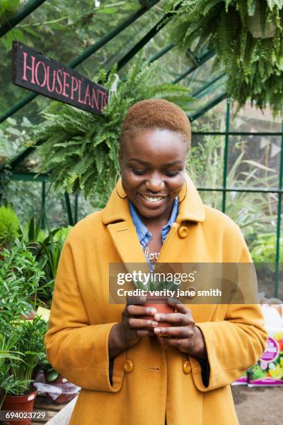 portrait of smiling black woman holding potted plant - jewellery shopping stock pictures, royalty-free photos & images