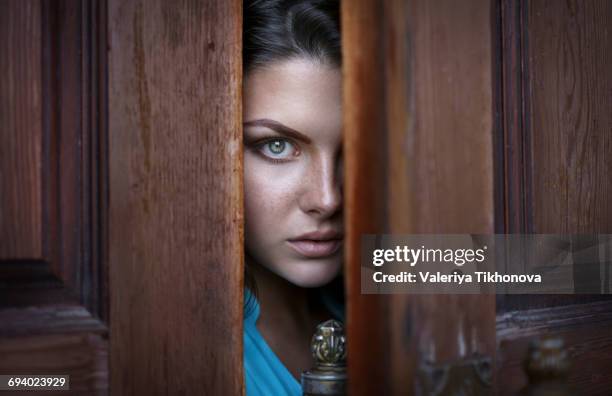 caucasian woman peeking in doorway - regarder à la dérobée photos et images de collection