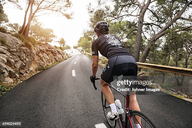 woman cycling on country road - female on bike stock-fotos und bilder