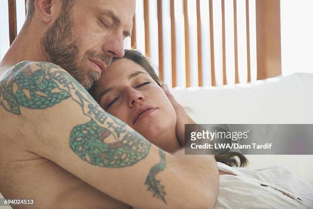 caucasian couple cuddling in bed - white dragon tattoo stock pictures, royalty-free photos & images