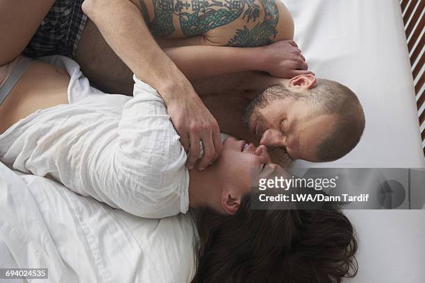 caucasian couple cuddling in bed - white dragon tattoo stock pictures, royalty-free photos & images