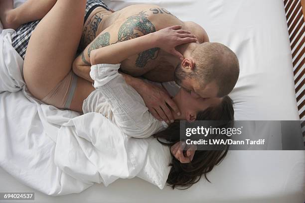 caucasian couple kissing in bed - man and woman kissing in bed stock-fotos und bilder