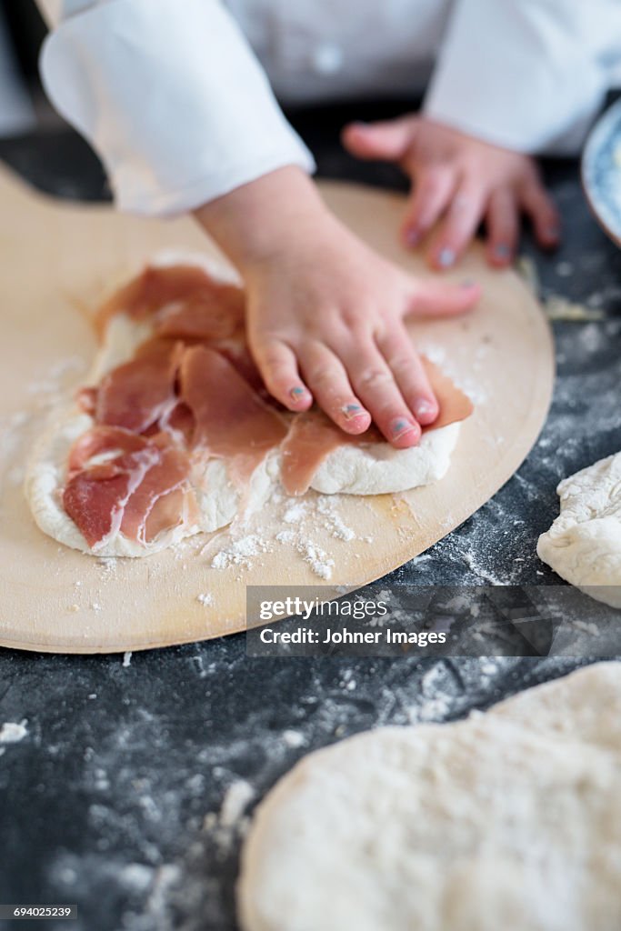 Child helping with making pizza