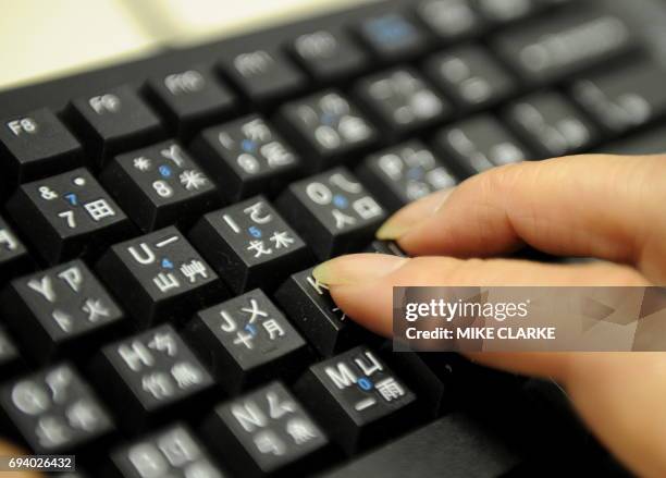 Woman uses a keyboard in Hong Kong on August 27, 2010 with keys illustrating both Roman letters and Chinese "radicals" or "particles" - parts of...