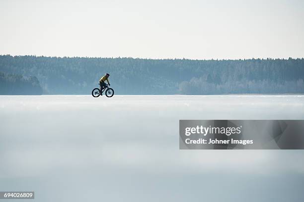 man cycling on a frozen lake - frozen lake stock pictures, royalty-free photos & images