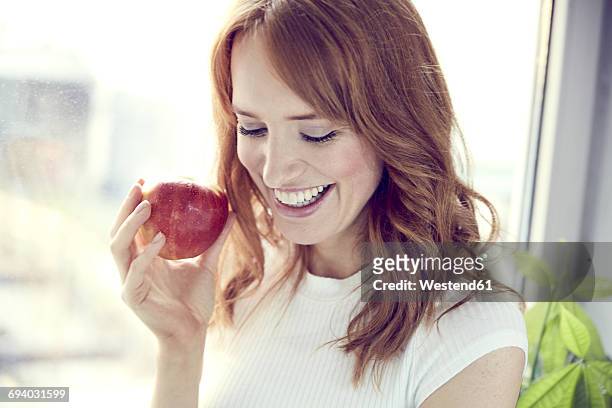 portrait of redheaded woman with red apple - adult female eating an apple stock pictures, royalty-free photos & images