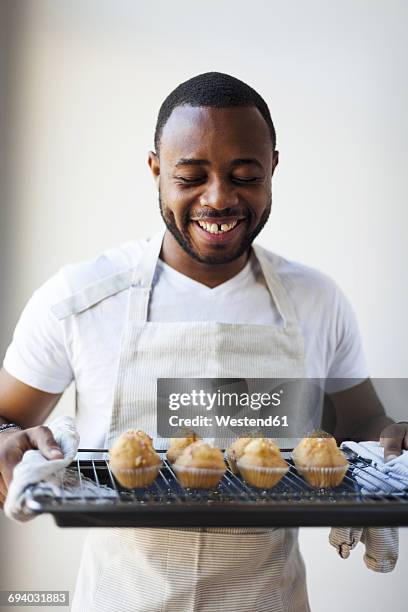 happy young man holding tray with muffins - man tray food holding stockfoto's en -beelden