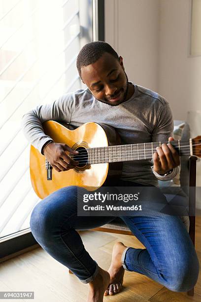 young man at home playing guitar - plucking an instrument stock pictures, royalty-free photos & images