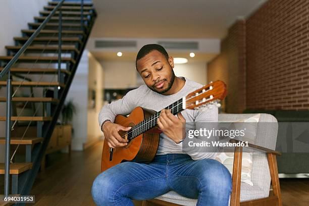 young man at home playing guitar - guitar imagens e fotografias de stock