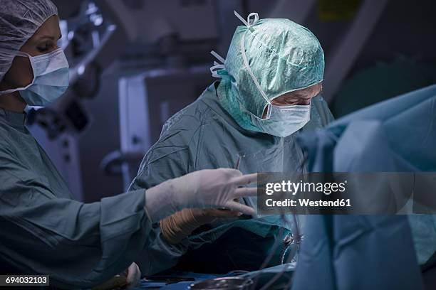 neurosurgeon with nurse closing operation wound - neurosurgery stock-fotos und bilder