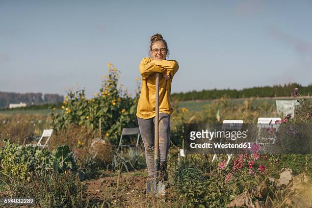 smiling young woman with spade in cottage garden - freizeitaktivität stock-fotos und bilder